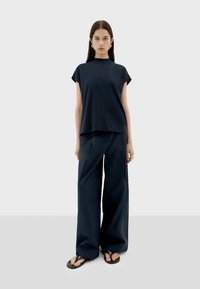 Marineblaue, lässig geschnittene T-Shirt mit kurzen Ärmeln, kombiniert mit lockeren, weiten Hosen. Beide aus glattem Stoff und mit einfachem Design.