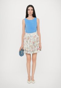 Blue sleeveless top paired with a floral ruffled skirt. Accessories include a blue clutch. Finished with light-colored, pointed flats.