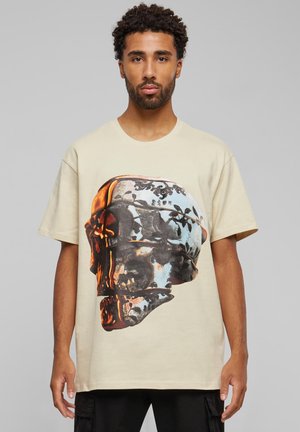 Beige bomulds T-shirt med et stort flerfarvet kraniet grafik med blomster mønstre og intrikate detaljer. Afslappet pasform og rund hals design.