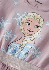 Robe courte à manches courtes rose ornée d'un personnage imprimé aux cheveux blonds et à la robe bleue, agrémentée d'une ceinture pailletée argentée et de motifs flocons de neige.