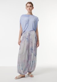 Lichtblauw gedrapeerd top met geplooide details, gecombineerd met losse, pastelbloemenpatronen broeken. Zachte stof met een relaxed fit.
