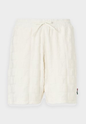 Pantaloncini bianchi strutturati con un motivo a rilievo. Vita elastica con cordoncino. Tasche laterali e rifiniture a contrasto sull'orlo.