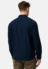 Marineblå langærmet skjorte lavet af letvægtsstof, med en klassisk krave, knaplukning ved håndleddene og en lige rygdesign.
