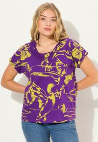 Paarse T-shirt met gele vogelillustraties; korte mouwen, ronde halslijn en een ontspannen pasvorm. Het materiaal lijkt zacht, waarschijnlijk katoen of jersey.