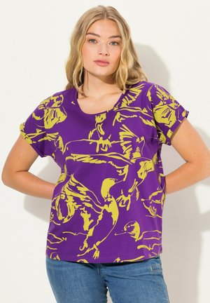 Camiseta morada con ilustraciones de pájaros amarillos; mangas cortas, cuello redondo y corte relajado. El material parece suave, probablemente algodón o jersey.