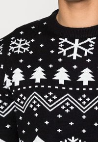 Svart stickad tröja med vit snöflinga, träd och geometriska mönster. Rund halsringning, strukturerad tyg med en klassisk passform.