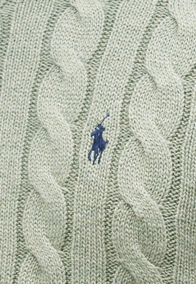 Tejido de punto verde claro con gruesos patrones de trenzas y un pequeño logotipo de un caballo y jinete en color azul marino bordado en el centro.