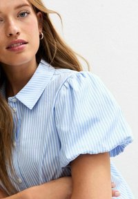 Light blue striped shirt featuring a classic collar and puff sleeves. The fabric appears smooth with a button-down front design.