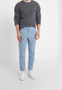 Grå fluffig tröja och ljusblå randiga byxor, kompletterade med vita sneakers. Outfiten är avslappnad och har en enkel design.