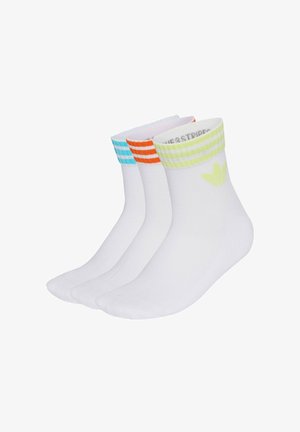 Trois paires de chaussettes blanches chevilles avec des bord-côtes à rayures vert clair, orange et bleu, chacune avec un petit logo trèfle.