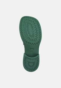 Semelle de chaussure en caoutchouc vert avec un motif en zigzag et une forme arrondie, présentant une finition lisse et une indication de taille (38) près du talon.
