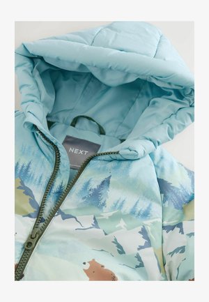 Svijetloplava jakna s kapuljačom od puf materijala s uzorkom šume i medvjeda, zeleni patentni zatvarač i mekan, glatki materijal. Oznaka glasi "NEXT."
