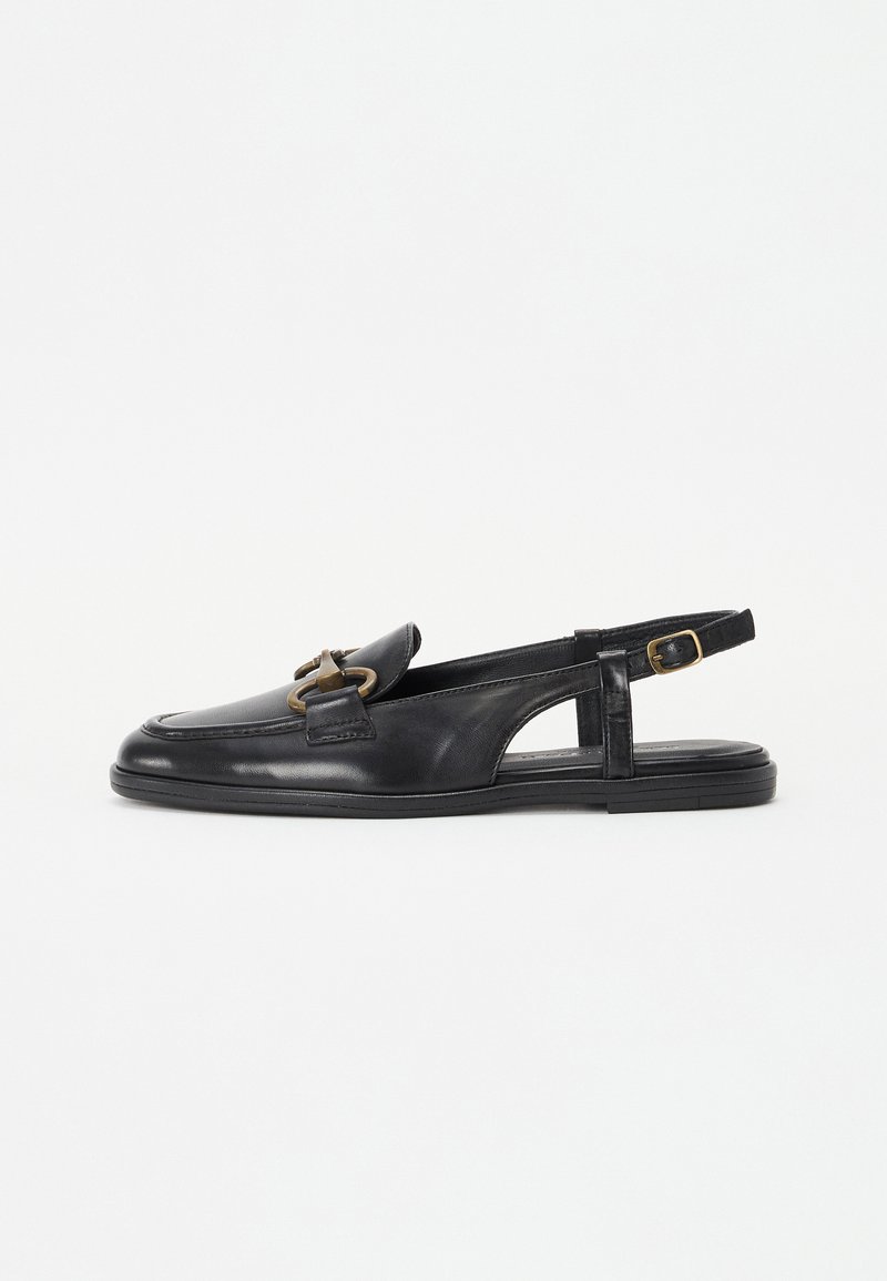 Chaussure en cuir noir à talon ouvert avec un bout arrondi, une semelle plate, et un détail en métal doré décoratif sur le dessus.