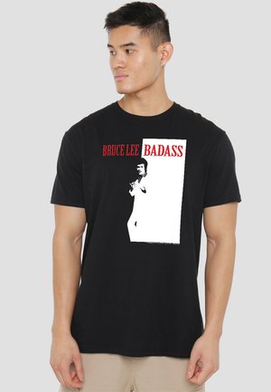 Black cotton t-shirt featuring a graphic print of Bruce Lee in white, with red text saying "BRUCE LEE BADASS." Crew neckline, short sleeves.