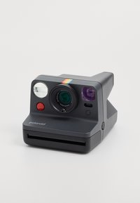 Polaroid instant camera in matte gray with a rounded design. Features include a lens, flash, and a colored stripe on top. Film slot at the front.