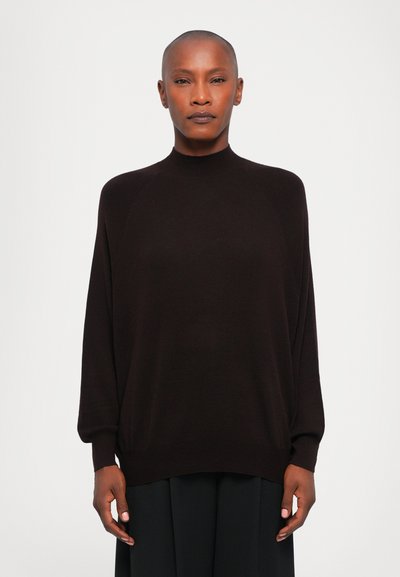 Pull à col haut, manches longues, marron foncé, en tissu doux avec une coupe décontractée et des poignets côtelés, associé à une jupe fluide.