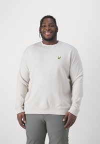 Sweatshirt beige chiaro con scollo rotondo, polsini e orlo a coste; presenta un piccolo logo ricamato giallo sul petto.