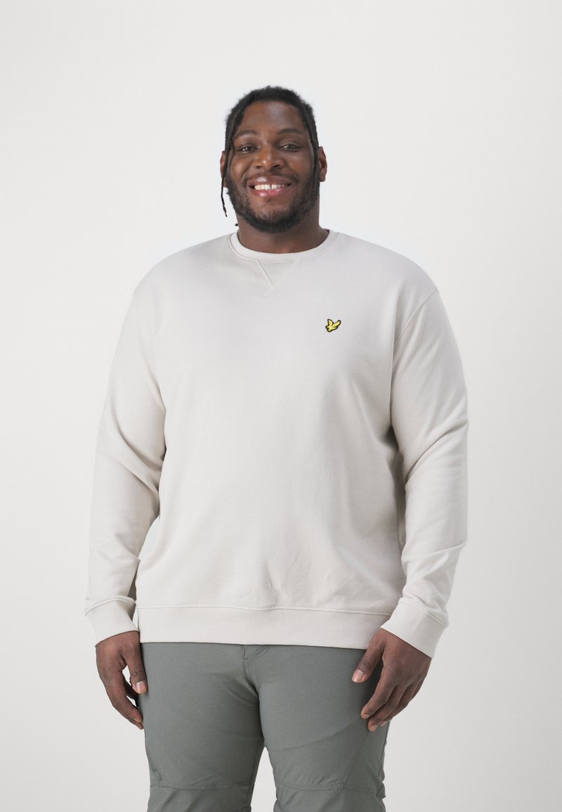 Sweatshirt beige chiaro con scollo rotondo, polsini e orlo a coste; presenta un piccolo logo ricamato giallo sul petto.