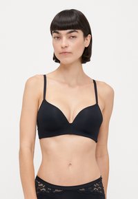 Black bra with smooth, stretchy fabric, plunging neckline, and adjustable thin straps. Features minimal seams and a sleek design.