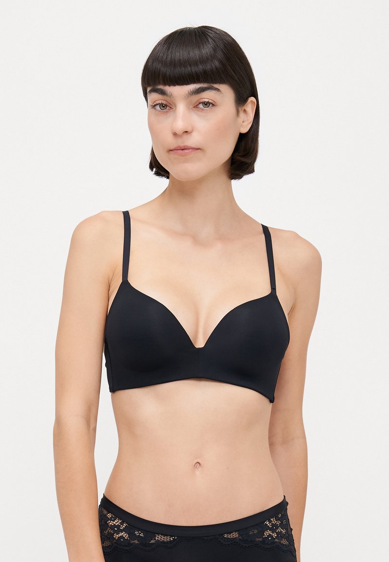 Black bra with smooth, stretchy fabric, plunging neckline, and adjustable thin straps. Features minimal seams and a sleek design.