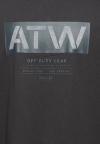 Dunkelgraues T-Shirt mit einem glänzenden Logo "ATW" in Hellgrau, darunter befindet sich der Schriftzug "OFF DUTY GEAR" sowie weitere Spezifikationen in ähnlichen Farben.
