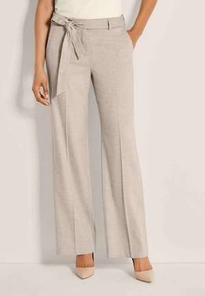 Pantalon beige taille haute à jambes larges avec ceinture nouée à l'avant, porté avec des talons nude à bout pointu et un top blanc.