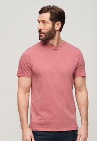 T-shirt a maniche corte con collo rotondo in rosa melange, dal fit rilassato. Tessuto morbido, texture sottile e design dell'orlo pulito.