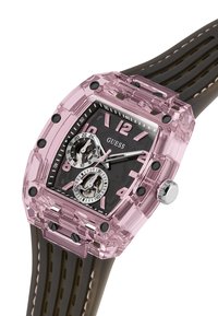 Élégant boîtier de montre rectangulaire transparent rose avec un cadran noir et des accents roses. Bracelet en caoutchouc brun avec des rainures. Deux sous-cadrans et couronne en argent.