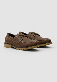 Zapatos de cuero marrón con un diseño clásico, que presentan costuras contrastantes, cordones en la parte delantera y una suela de goma con relieve para mayor tracción.
