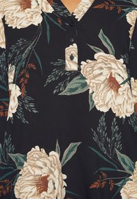 Tessuto nero con grandi fiori di peonia crema e foglie verdi, caratterizzato da scollatura a V e dettagli con placket a tre bottoni.