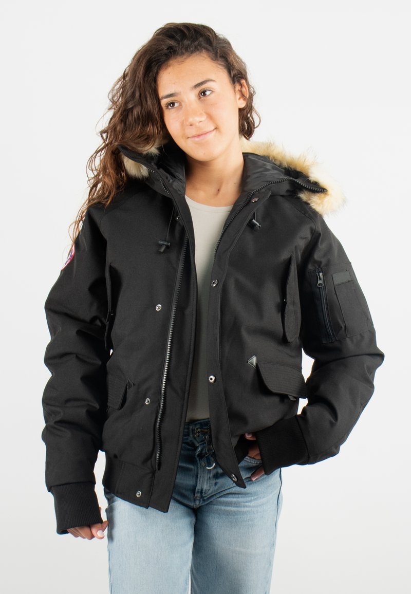 Veste noire isolée avec capuche doublée en fourrure, fermetures éclair et bouton-pression, plusieurs poches et poignets côtelés. Texture lisse, matériau durable.