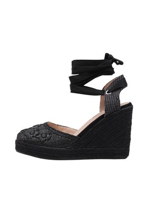Espadrille compensée noire avec broderie florale, lien à nouer autour de la cheville et détails de sangle texturée.