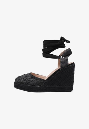 Espadrille compensée noire avec broderie florale, lien à nouer autour de la cheville et détails de sangle texturée.