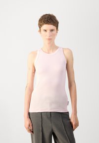 Lys rosa, tettsittende tanktop med rund halslinning og tynne stropper. Laget av et glatt, elastisk stoff, med et lite merke ved kanten.