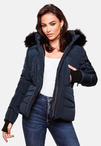 Navy blue puffer jacket with faux fur hood, zippered pockets, and ribbed cuffs. Features a quilted texture and lightweight material.