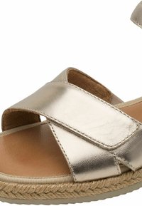 Sandales métalliques argentées avec brides croisées, semelle intérieure rembourrée et semelle enveloppée de jute. Texture lisse avec des accents cousus.