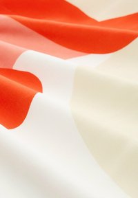 Textilná tkanina so zobrazením veľkých abstraktných tvarov v jasne červenej a jemne broskyňovej farbe na béžovom pozadí. Hladká textúra s lesklým povrchom.