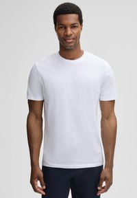 Witte t-shirt met korte mouwen, gemaakt van katoen, met een ronde halslijn en een eenvoudig ontwerp, gedragen door een model.
