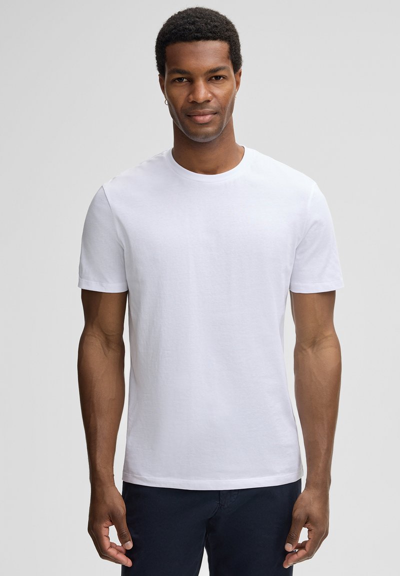 Witte t-shirt met korte mouwen, gemaakt van katoen, met een ronde halslijn en een eenvoudig ontwerp, gedragen door een model.