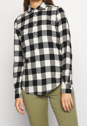 Camisa de cuadros en blanco y negro con cuello, mangas largas y cierre delantero con botones; confeccionada en una tela suave y texturizada.