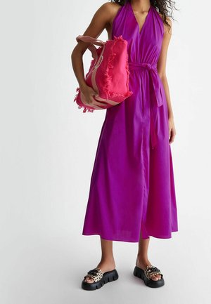 Fialové šaty na holá ramena s páskem na zavázání, doplněné o růžovou kabelku s třásněmi a černé nazouvací sandály se vzorem leopardí srsti na pásku.