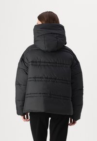 Zwarte pufferjack met een hoge kraag en een vaste capuchon, met horizontaal gequiltde secties en een losse, oversized pasvorm.