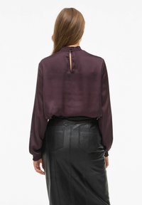 Bordeaux satinbluse med lange ærmer og nøglehul tilbage, paired med en sort læder blyantskirt med lommer og syning detaljer.
