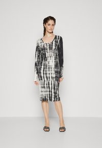 Long-sleeve dress in black and white tie-dye pattern, fitted design, scoop neckline, mid-calf length, fabric appears smooth and stretchy.