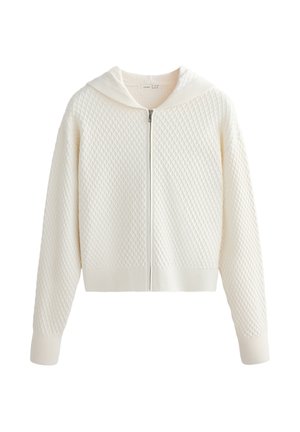 Bela pletena jopa z zadrgo, teksturiranim vzorcem diamantov, dolgimi rokavi in rebrastimi manšetami ter spodnjim robom.