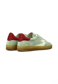 Un paio di sneaker in suede verde chiaro con linguette rosse sul tallone, suole in gomma, accenti crema e il marchio "MASTER CLUB" di lato.
