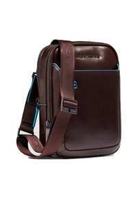 Bolso bandolera de cuero marrón con detalles en azul, cierre de cremallera, correa ajustable y bolsillo frontal. Textura suave y forma rectangular compacta.