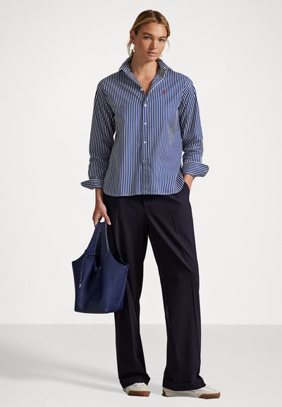 Cămașă cu dungi, cu nasturi, în albastru și alb, asortată cu pantaloni bleu închis și o geantă texturată în nuanță de bleu închis. Material neted, croială lejeră și mâneci lungi.