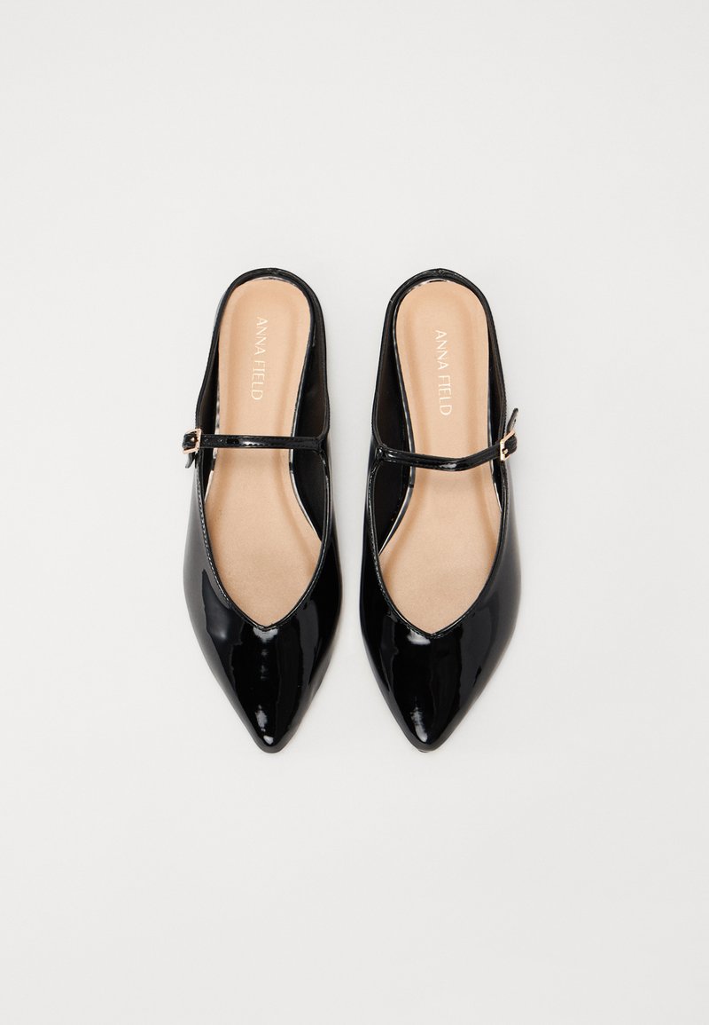 Des chaussures slingback en cuir verni noir avec un bout pointu et une bride à la cheville. Texture lisse avec un design minimaliste. Semelle intérieure beige visible.