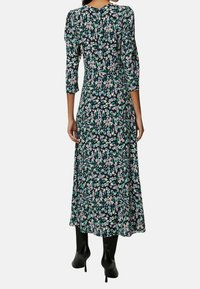 Abito maxi floreale con maniche a tre quarti, caratterizzato da uno sfondo blu scuro e un motivo floreale multicolore. Tessuto dalla consistenza liscia.